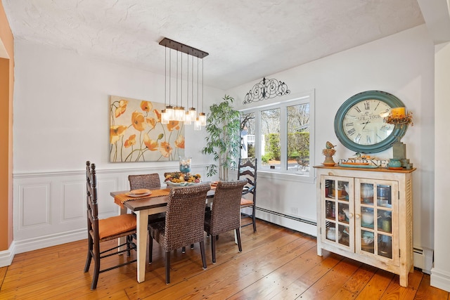 dining area featuring a baseboard radiator and hardwood / wood-style flooring