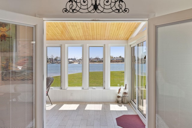 unfurnished sunroom featuring lofted ceiling, a water view, and wood finished floors