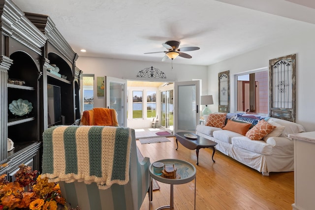 living area featuring french doors, recessed lighting, ceiling fan, a water view, and light wood-style floors