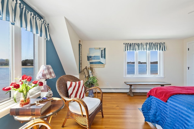 bedroom with a water view, a baseboard radiator, and light wood finished floors
