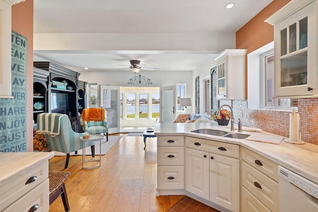 kitchen with a ceiling fan, white dishwasher, a sink, open floor plan, and light countertops