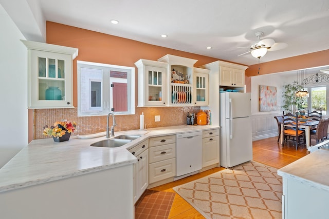 kitchen featuring light wood finished floors, light countertops, a sink, and white appliances