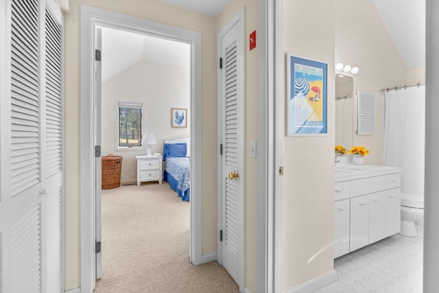 hall with lofted ceiling, baseboards, a sink, and light colored carpet