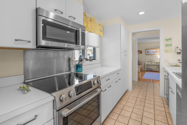 kitchen featuring light tile patterned floors, white cabinets, stainless steel appliances, light countertops, and a sink