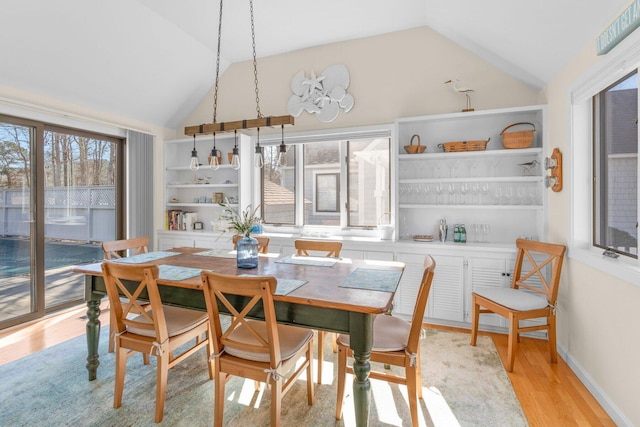 dining room featuring vaulted ceiling, plenty of natural light, and light wood finished floors