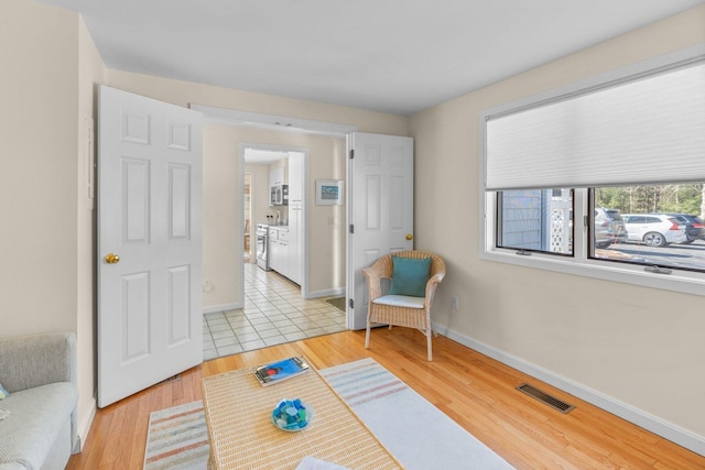 living area featuring light wood-style floors, baseboards, and visible vents