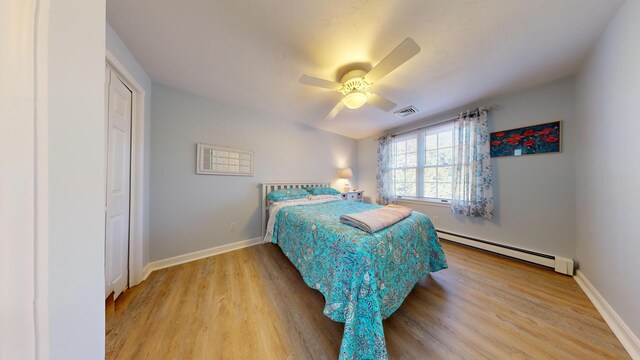 bedroom featuring ceiling fan, a baseboard heating unit, and light wood-type flooring