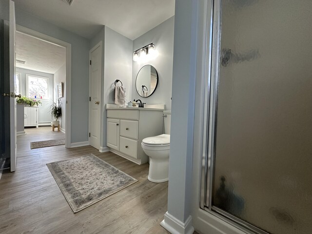 bathroom featuring hardwood / wood-style flooring, vanity, toilet, and a shower with shower door