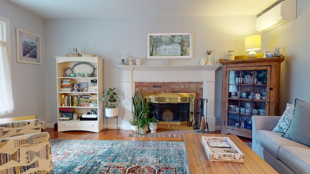 living room featuring a fireplace, wood finished floors, baseboards, and a wall mounted AC