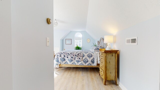 bedroom with lofted ceiling and light hardwood / wood-style floors