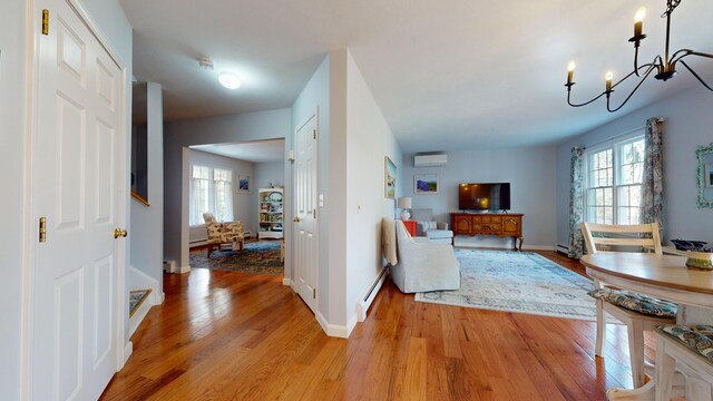 interior space featuring a healthy amount of sunlight, a notable chandelier, light wood-type flooring, and baseboard heating