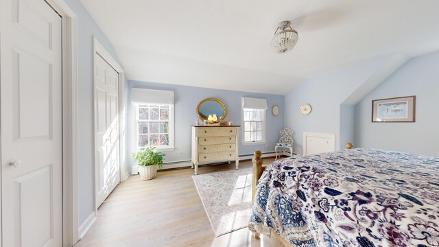 bedroom with vaulted ceiling, light hardwood / wood-style floors, and a baseboard radiator