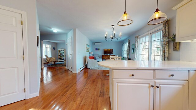 kitchen with decorative light fixtures, a wealth of natural light, light hardwood / wood-style flooring, and white cabinets