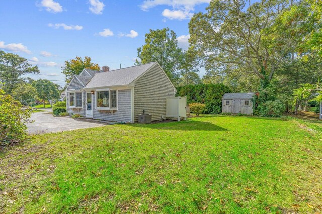 11 Joe Lincoln Rd, West Harwich, MA 02671 - view of property exterior featuring a patio, a chimney, an outdoor structure, a storage unit, and a lawn