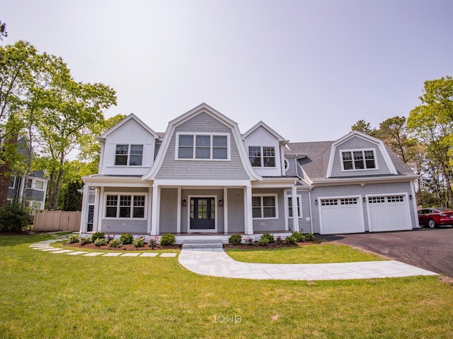 view of front of home featuring covered porch, a front yard, and a garage