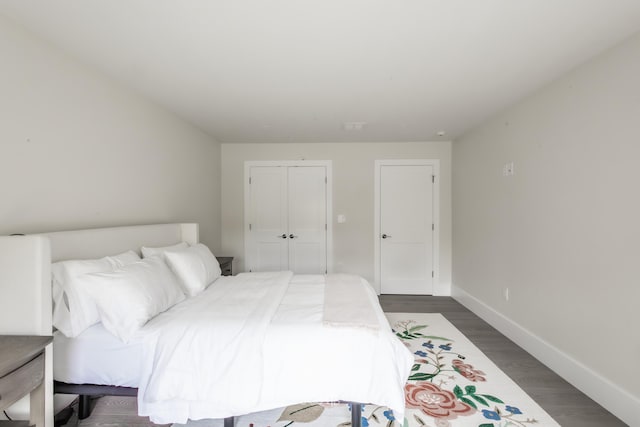 bedroom with dark hardwood / wood-style flooring and a closet