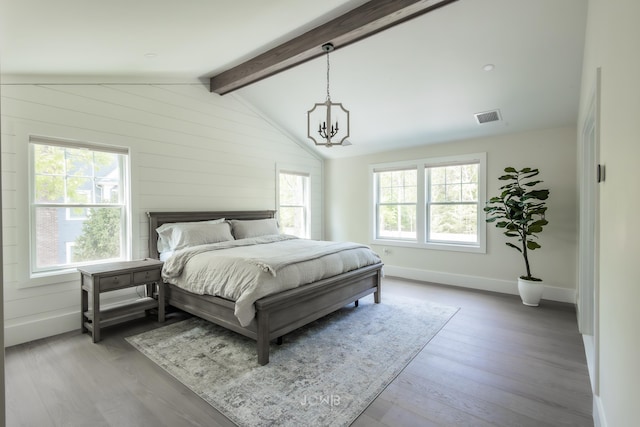 bedroom with an inviting chandelier, light hardwood / wood-style flooring, and vaulted ceiling with beams