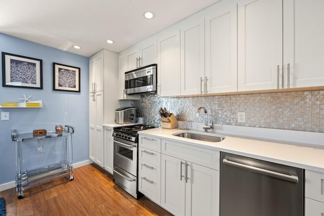 kitchen featuring light countertops, a sink, wood finished floors, and stainless steel appliances
