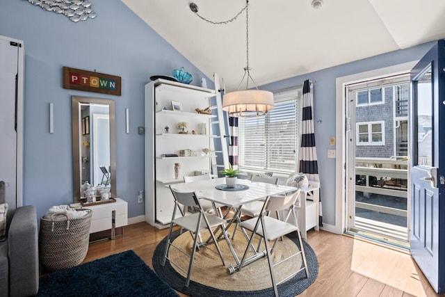 dining room featuring baseboards, a chandelier, lofted ceiling, and light wood-type flooring