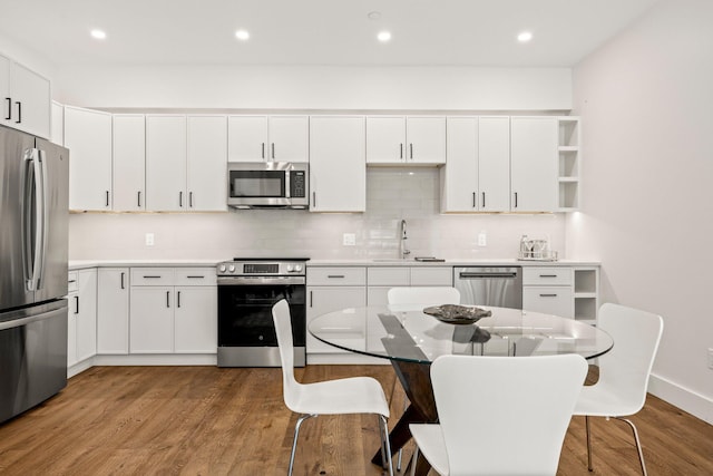 50 Nelson Ave Unit 4, Provincetown, MA 02657 - kitchen featuring appliances with stainless steel finishes, a breakfast bar area, open shelves, backsplash, and wood finished floors