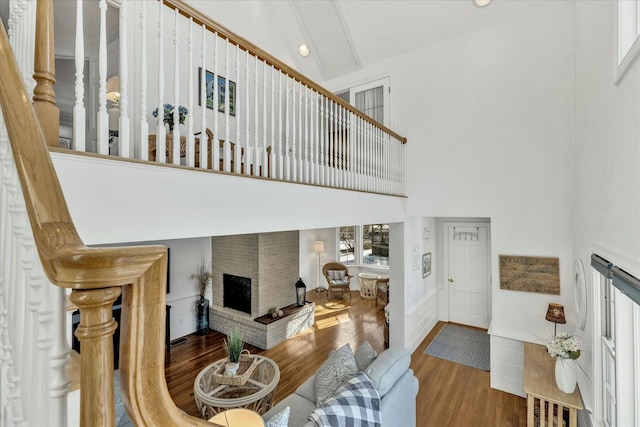 living room featuring high vaulted ceiling, hardwood / wood-style floors, and a brick fireplace