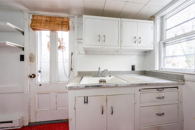 kitchen with sink, white cabinets, and baseboard heating