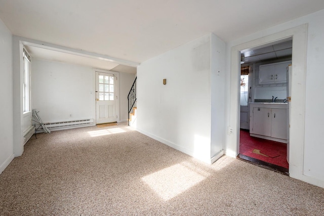 carpeted empty room with a baseboard heating unit and sink