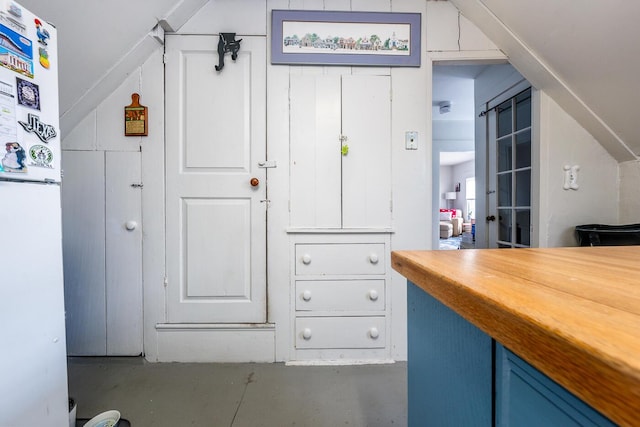 kitchen featuring white refrigerator, wood counters, and blue cabinets