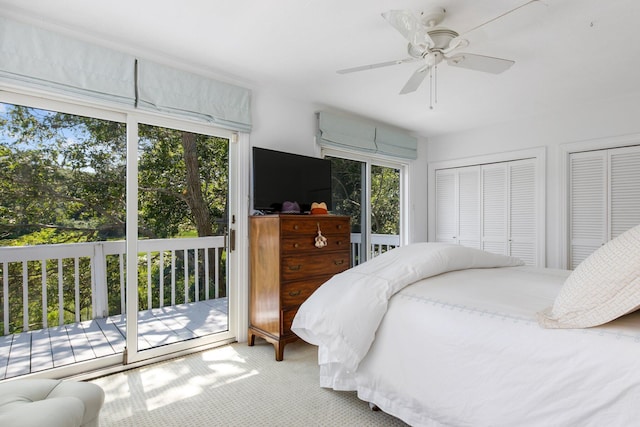 carpeted bedroom featuring multiple windows, access to exterior, two closets, and a ceiling fan