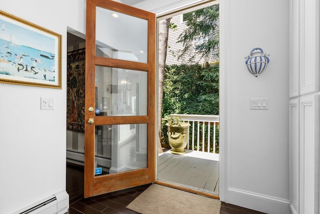 doorway with baseboard heating, a baseboard heating unit, dark wood-style flooring, and baseboards