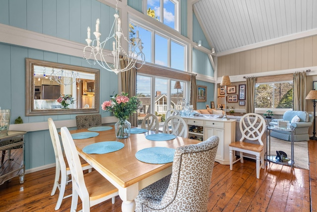 dining area featuring high vaulted ceiling, an inviting chandelier, and hardwood / wood-style flooring