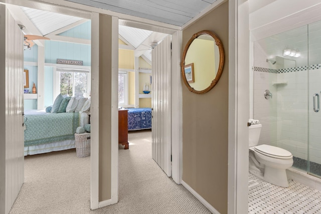 bathroom featuring connected bathroom, toilet, a shower stall, and baseboards