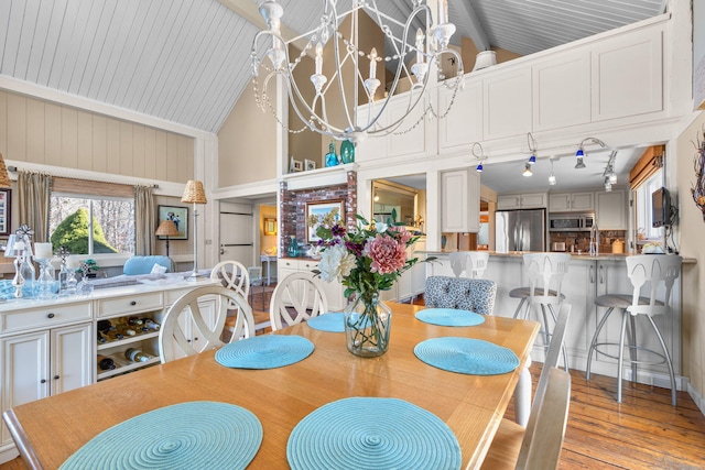 dining space featuring high vaulted ceiling, an inviting chandelier, and light wood-style flooring