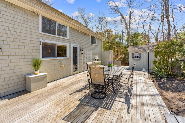 deck with an outbuilding, outdoor dining space, and a shed