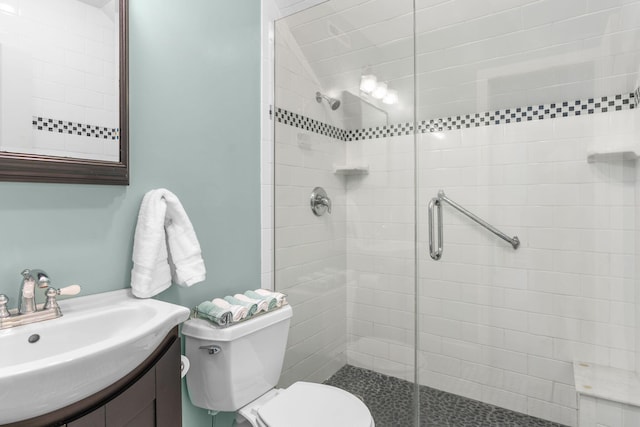 full bathroom featuring vanity, a shower stall, and toilet