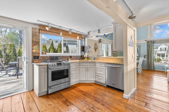 kitchen with a sink, rail lighting, light wood-style floors, and stainless steel appliances