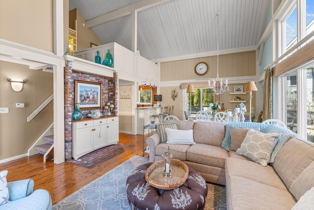 living room featuring beamed ceiling, a notable chandelier, high vaulted ceiling, hardwood / wood-style flooring, and stairway