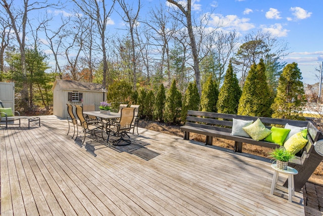 wooden terrace with outdoor dining space, a shed, and an outdoor structure