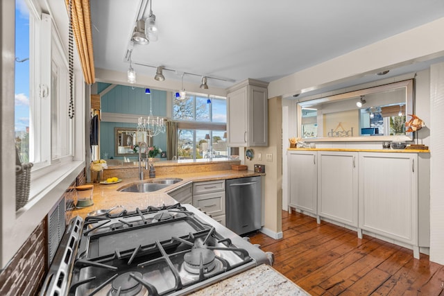 kitchen featuring light stone counters, an inviting chandelier, a sink, stainless steel appliances, and hardwood / wood-style flooring