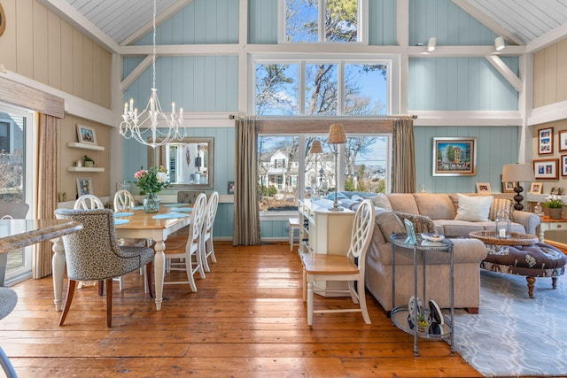 dining space featuring hardwood / wood-style flooring, a notable chandelier, and high vaulted ceiling