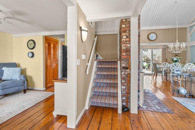 staircase featuring baseboards, ceiling fan with notable chandelier, and hardwood / wood-style flooring