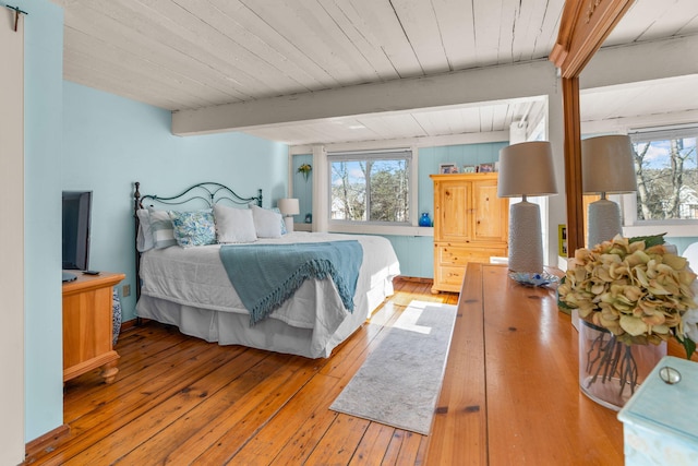 bedroom featuring beam ceiling, light wood-style flooring, and wood ceiling