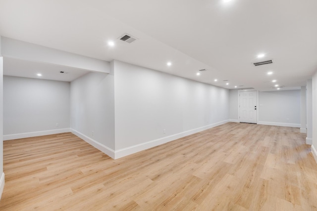 finished basement with baseboards, visible vents, and light wood-style floors