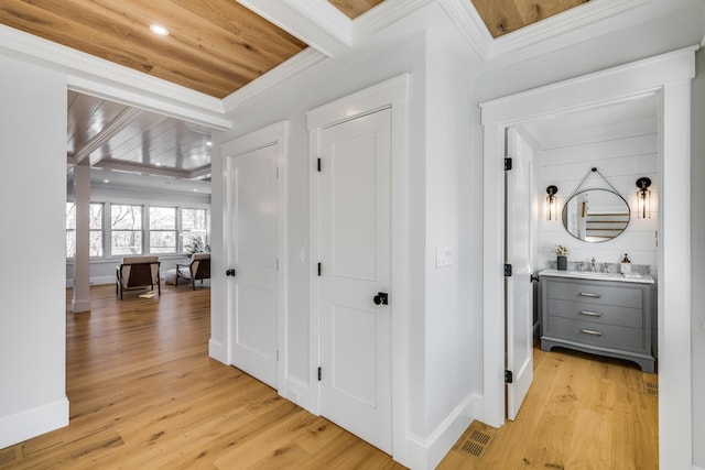 corridor with wooden ceiling, visible vents, baseboards, light wood finished floors, and crown molding