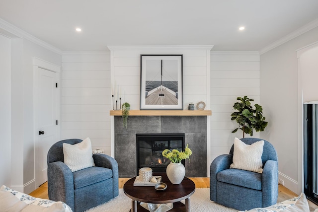 living room with ornamental molding, baseboards, light wood-style flooring, and a tiled fireplace