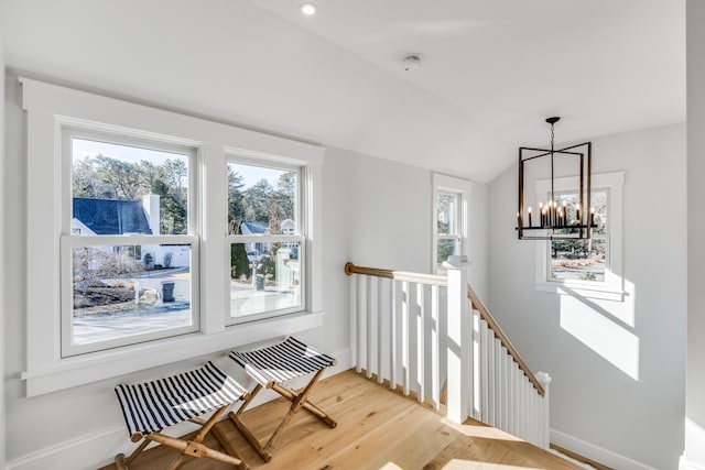 stairway featuring a chandelier, lofted ceiling, baseboards, and wood finished floors