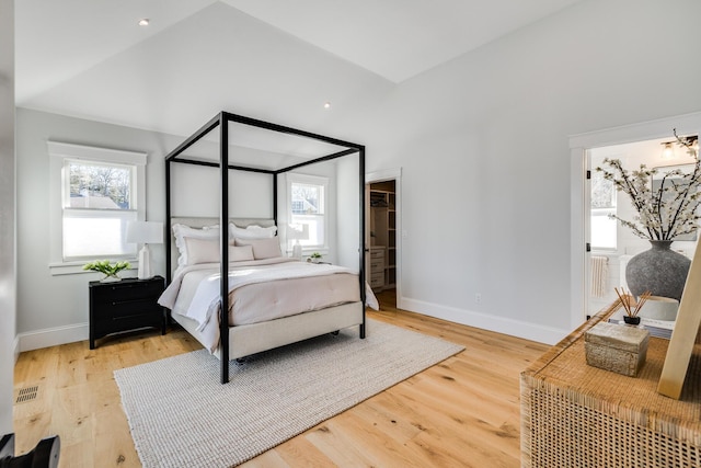 bedroom with light wood-type flooring, lofted ceiling, and baseboards