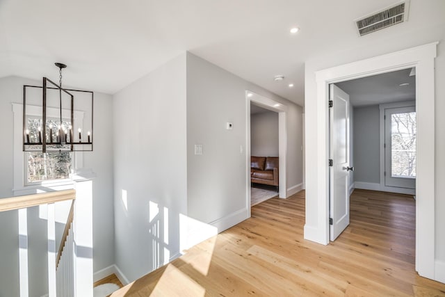 hall featuring light wood finished floors, visible vents, an upstairs landing, a notable chandelier, and recessed lighting