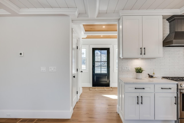 interior space with wall chimney range hood, wood ceiling, ornamental molding, and stainless steel range with gas stovetop