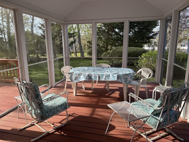 sunroom featuring outdoor dining area, hardwood / wood-style flooring, a wooden deck, and lofted ceiling